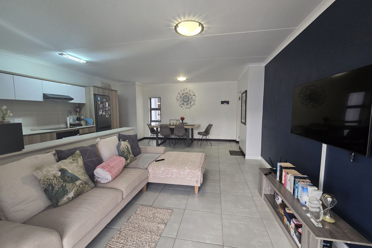 Spacious open-plan living area featuring a modern kitchen with built-in cabinetry, tiled flooring, and a striking dark blue accent wall.