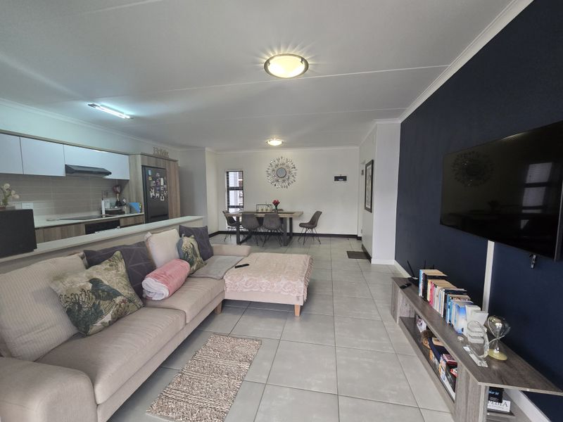 Spacious open-plan living area featuring a modern kitchen with built-in cabinetry, tiled flooring, and a striking dark blue accent wall.