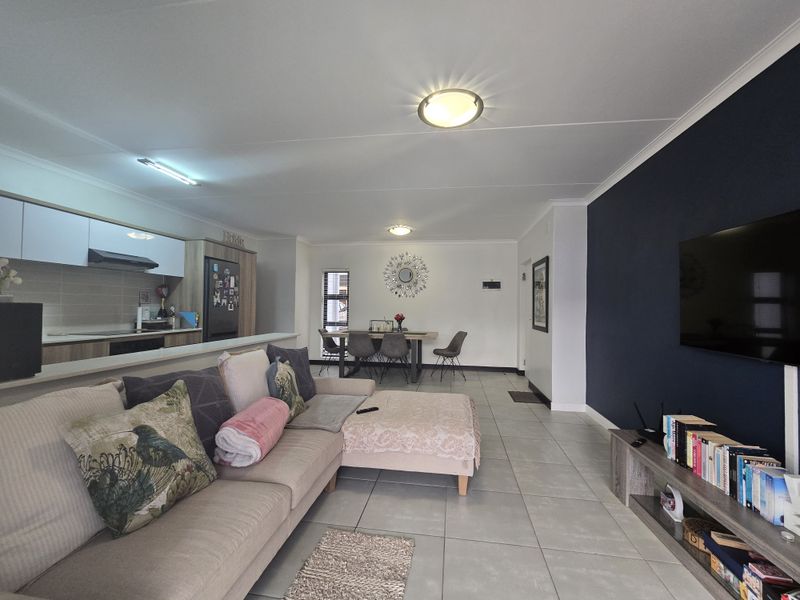 Spacious open-plan living area featuring a modern kitchen with built-in cabinetry, tiled flooring, and a distinct navy accent wall.