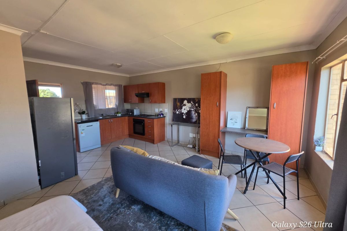 Open-plan living area featuring a functional kitchen with built-in cabinetry, oven, hob, and tiled flooring throughout the space.