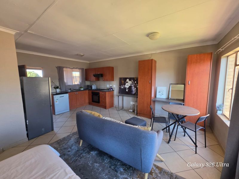 Open-plan living area featuring a functional kitchen with built-in cabinetry, oven, hob, and tiled flooring throughout the space.