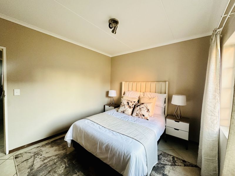 A well-maintained bedroom featuring neutral wall tones, tiled flooring, and a modern ceiling-mounted spotlight fixture.