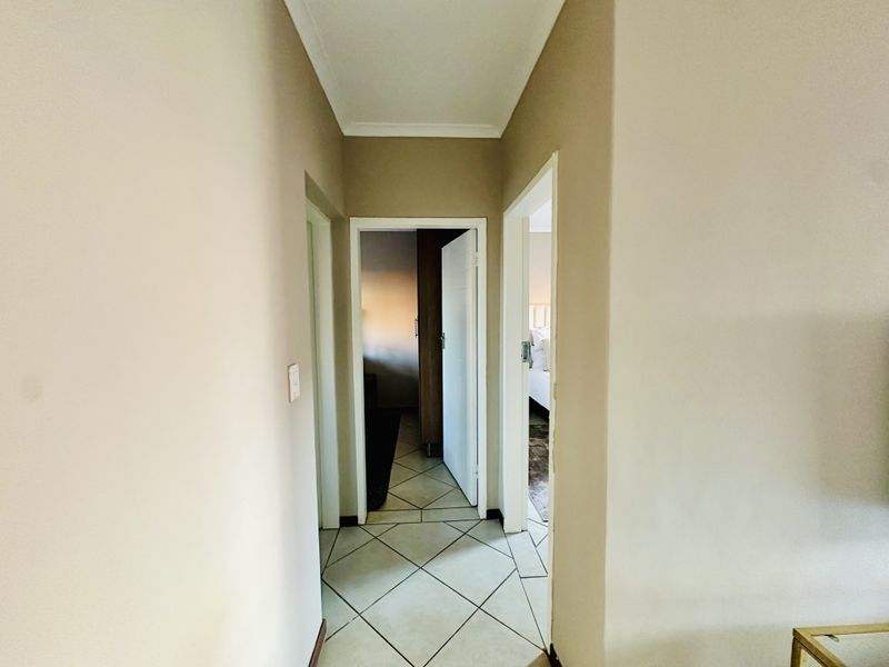 A clean, neutral-toned hallway featuring tiled flooring and access to adjacent rooms.