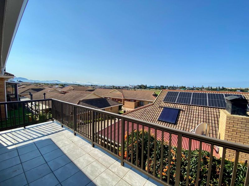 An elevated balcony featuring tiled flooring and a metal balustrade, offering expansive views over the surrounding residential neighborhood.