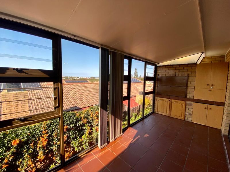 Enclosed patio area featuring tiled flooring, built-in cabinetry, and large windows offering an elevated view of the surrounding neighbourhood.