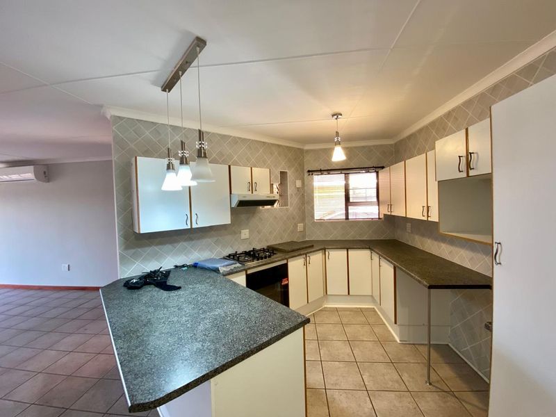 Functional kitchen featuring built-in cabinetry, gas hob, oven, extractor fan, and tiled finishes, offering a practical layout for daily cooking and meal preparation.