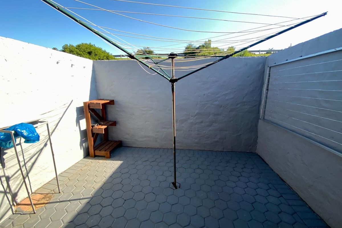 A private rear courtyard area featuring paved flooring and boundary walls, equipped with a rotary clothesline for laundry drying.