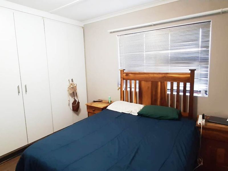 A functional bedroom featuring built-in cupboards and venetian blinds, providing essential storage and light control.