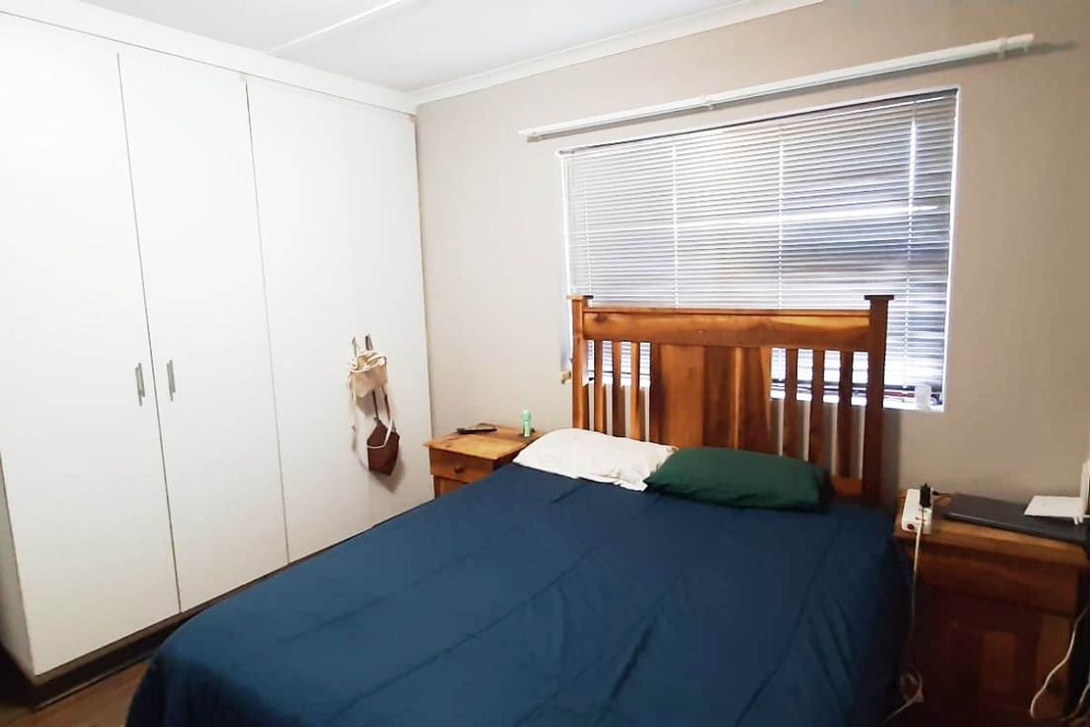 A functional bedroom featuring built-in cupboards and venetian blinds, providing essential storage and light control.