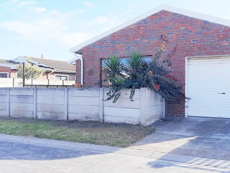 Front view of a face brick house featuring a single garage, concrete driveway, and precast concrete boundary wall.