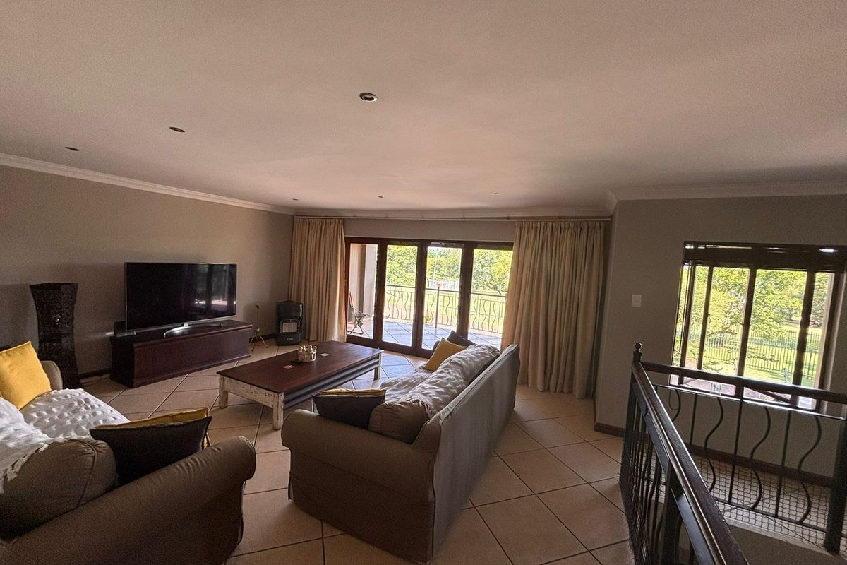 Spacious living room featuring tiled flooring, recessed lighting, and large sliding doors leading to an outdoor balcony with a wrought iron staircase railing.