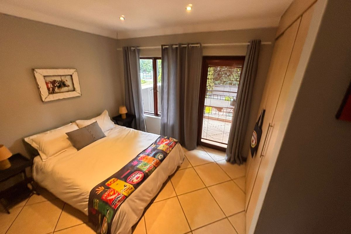 A well-maintained bedroom featuring tiled flooring, built-in cupboards, recessed lighting, and direct access to an outdoor patio area through a sliding glass door.