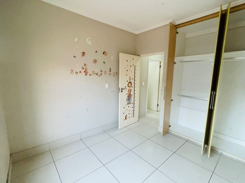 A vacant bedroom featuring tiled flooring and a built-in wardrobe, providing a clean canvas for personalization.