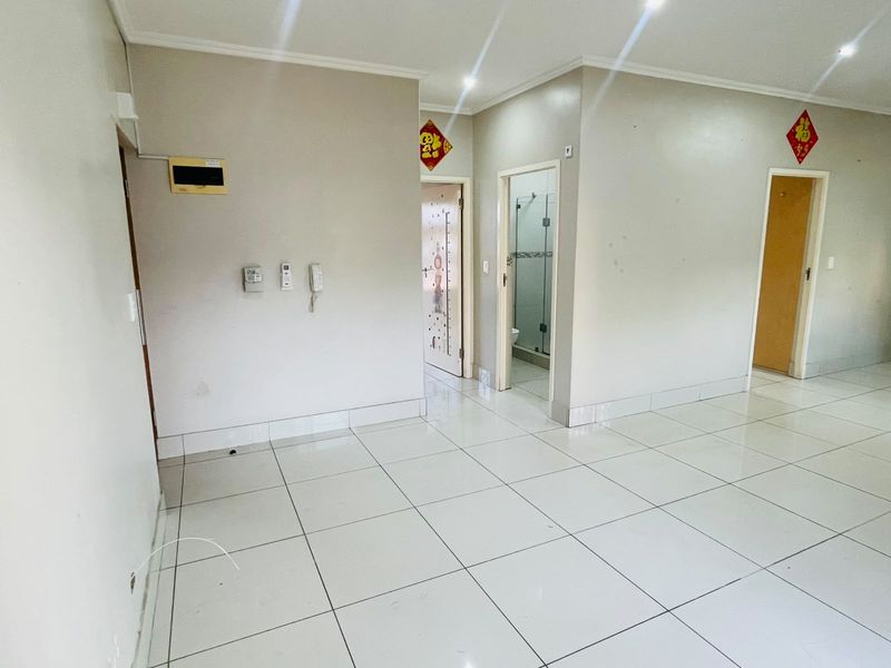 A bright, tiled hallway featuring recessed lighting, an intercom system, and access to multiple rooms within the apartment.