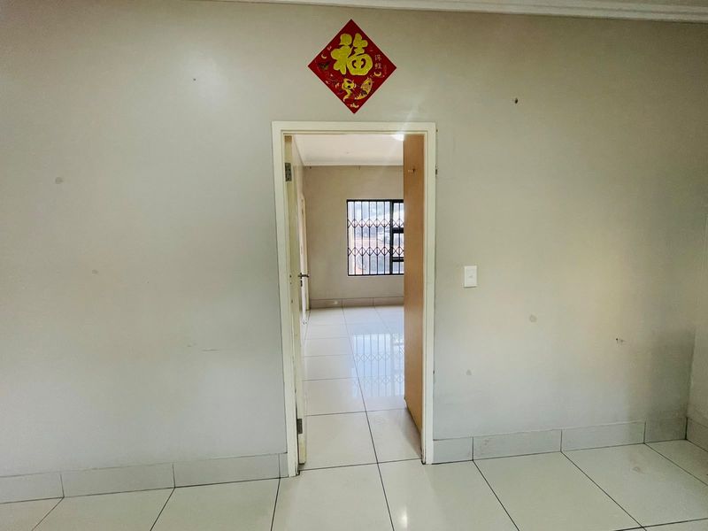 A view through a doorway into an empty room featuring tiled flooring and a security gate on the window.