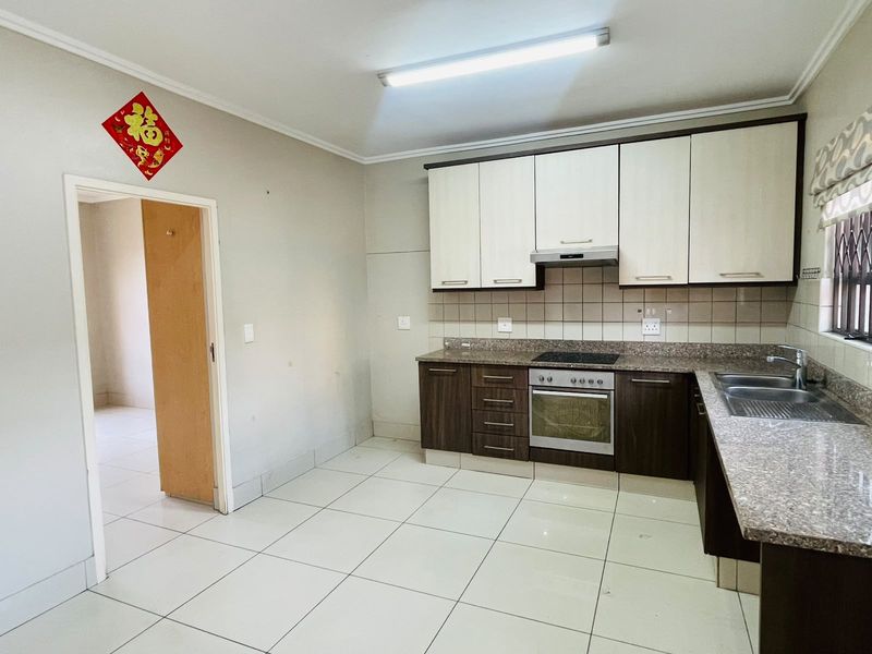 A functional kitchen featuring two-tone cabinetry, granite countertops, built-in oven and hob, and tiled flooring throughout.