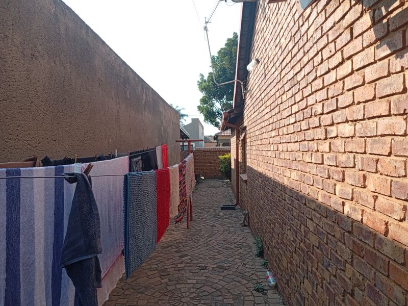 A side passage of the property featuring a brick exterior wall and paved walkway.