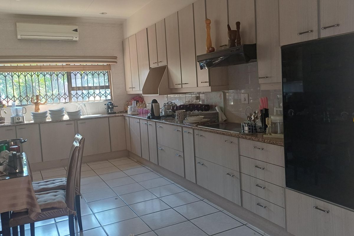 A functional kitchen featuring extensive built-in cabinetry, tiled flooring, an integrated oven, and a wall-mounted air conditioning unit.