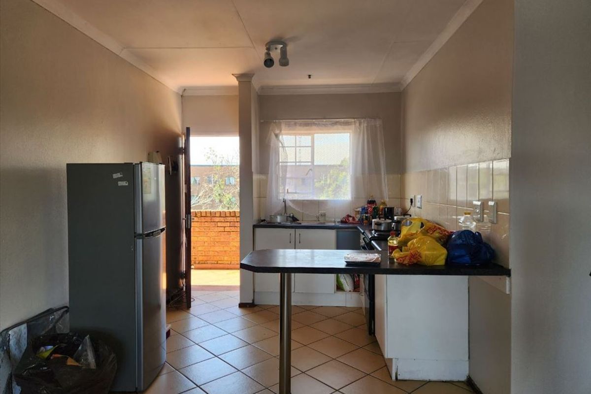 A functional kitchen area featuring tiled flooring, built-in cabinetry with a breakfast bar, and direct access to an outdoor balcony space.