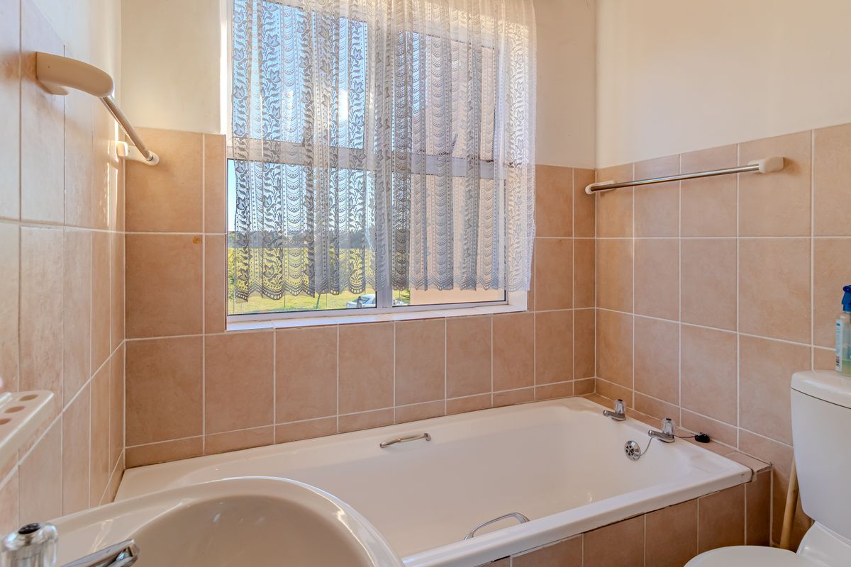 A functional bathroom featuring a built-in bathtub, ceramic wall tiling, and standard sanitary fixtures, offering a clean and practical space.