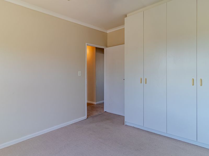 A clean, empty bedroom featuring neutral walls, carpeted flooring, and ample built-in cupboard storage space.