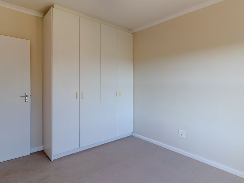 A clean, empty bedroom featuring neutral walls, carpeted flooring, and ample built-in cupboard storage space.