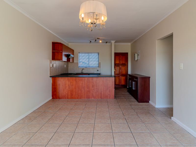 Open-plan living and kitchen area featuring tiled flooring, built-in wooden cabinetry, and a functional kitchen layout.