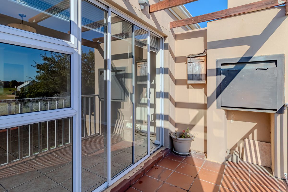 A covered balcony featuring tiled flooring, a built-in braai, and a timber pergola, offering an ideal space for outdoor entertaining.