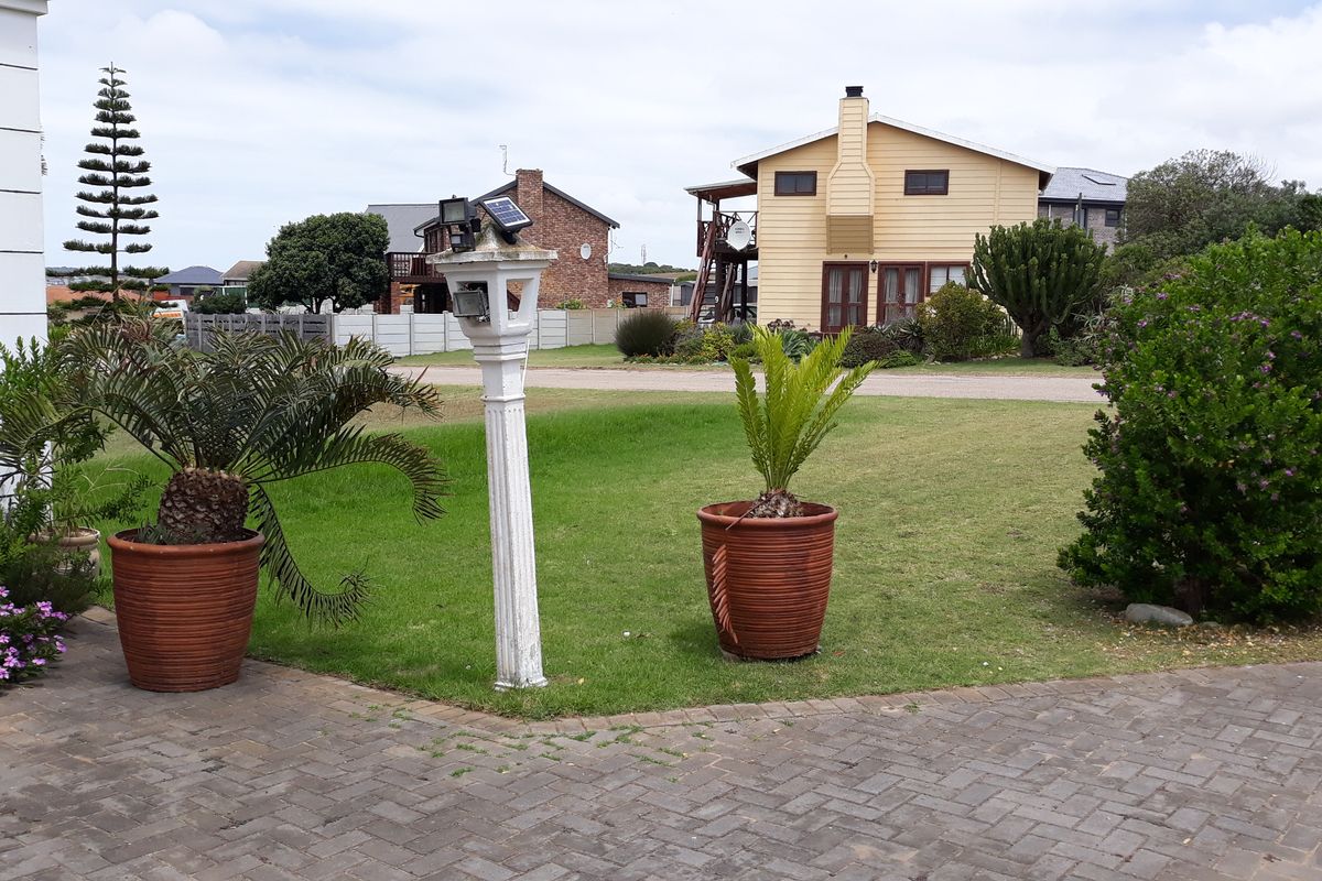A view of the rear garden area featuring a paved driveway, established lawn, and garden lighting.
