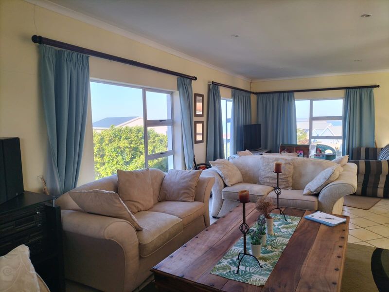 Spacious living room featuring large windows that provide ample natural light and views, complemented by tiled flooring and recessed ceiling lighting.