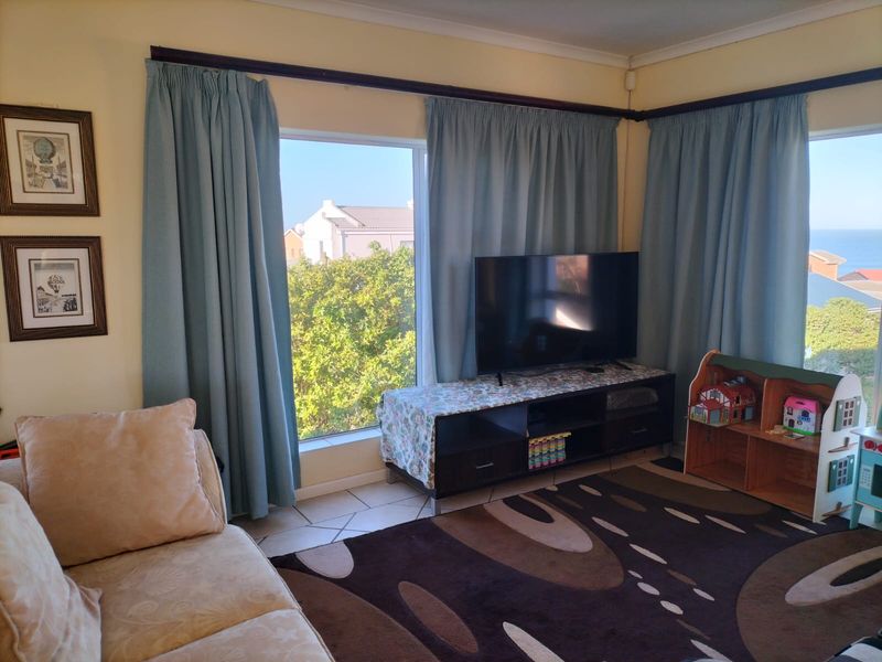 A living room featuring tiled flooring and large windows that provide natural light and views of the surrounding area.