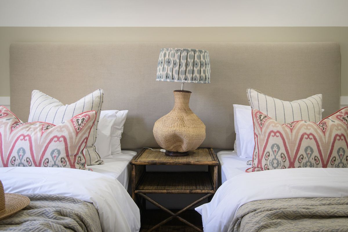 A well-maintained bedroom featuring a large, neutral-toned upholstered headboard spanning the width of the twin bed arrangement.