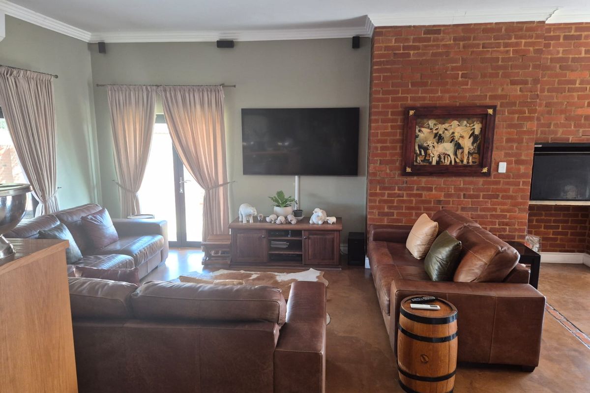 Spacious living room featuring a prominent exposed brick wall with a built-in fireplace, polished concrete floors, and direct access to the outdoor area.