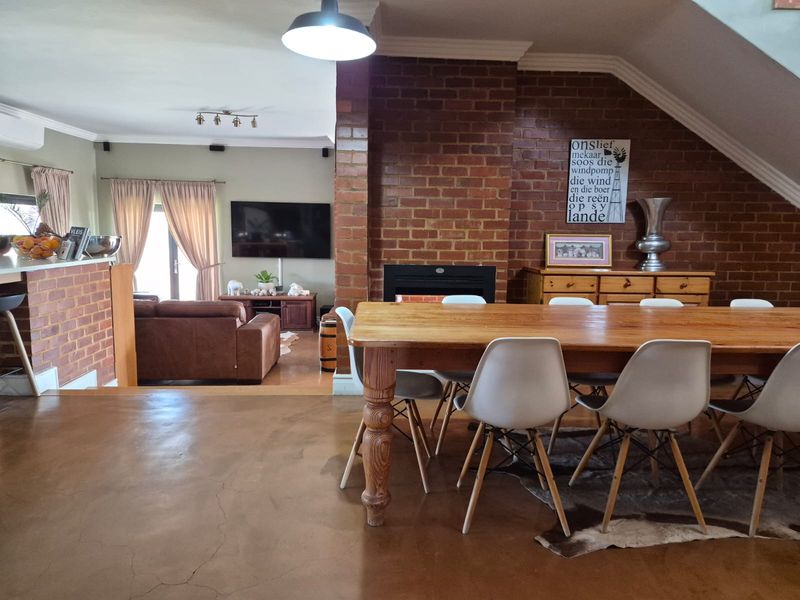 Spacious open-plan living and dining area featuring polished concrete floors, a prominent exposed brick fireplace, and direct access to the living space.