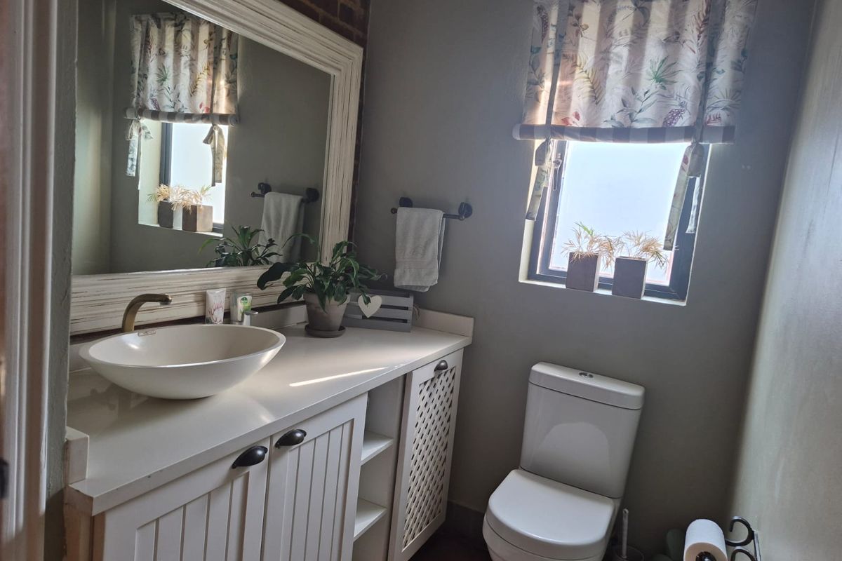 A well-maintained bathroom featuring a vessel sink, vanity cabinet, and an exposed brick accent wall, providing a charming and functional space.