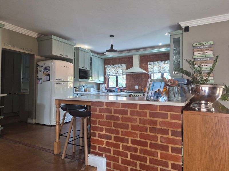 A charming kitchen featuring exposed brick accents, shaker-style cabinetry, stone countertops, and a functional breakfast bar layout.