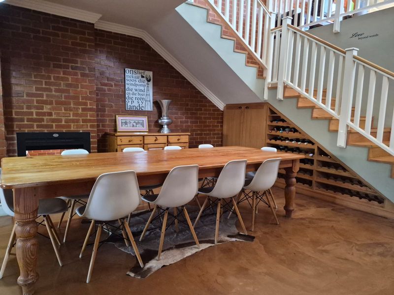 Dining area featuring exposed brick walls, polished concrete floors, a built-in fireplace, and custom under-stair wine storage and cabinetry.