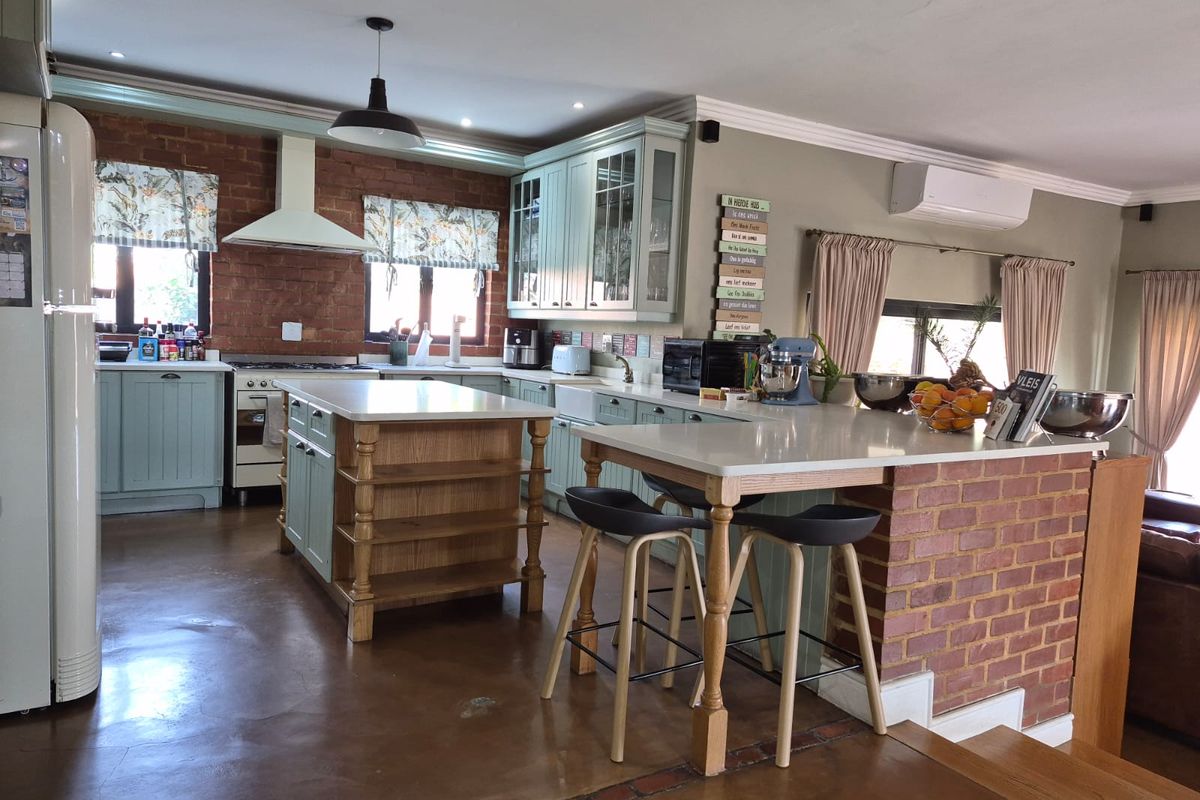 Spacious kitchen featuring a central island, breakfast bar, exposed brick accents, and custom cabinetry, creating a warm and functional culinary space.