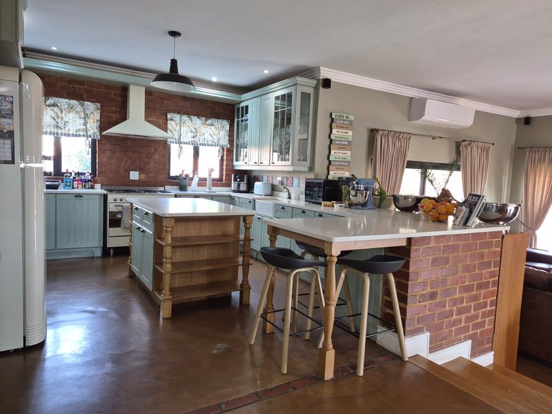 Spacious kitchen featuring a central island, breakfast bar, exposed brick accents, and custom cabinetry, creating a warm and functional culinary space.