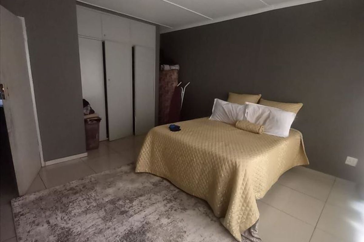 A bedroom featuring tiled flooring and built-in cupboards, providing functional storage space within the apartment.