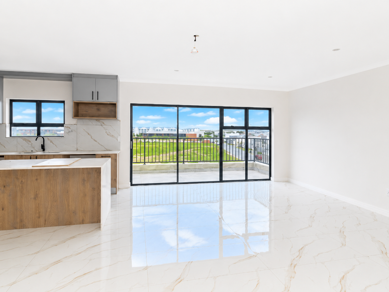 Modern open-plan living area featuring a sleek kitchen with stone countertops, marble-look floor tiles, and large sliding doors leading to a balcony.