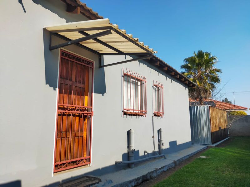 Rear exterior view of the property featuring a security gate, window bars, and an attached awning over the entrance.