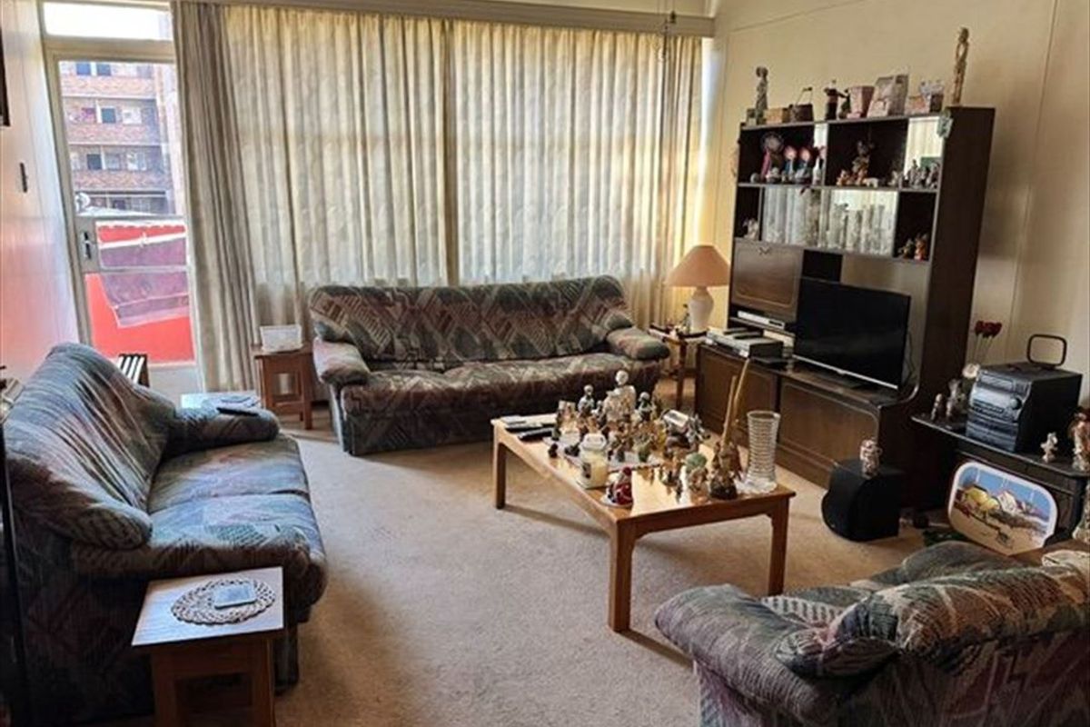 A spacious living room featuring carpet flooring, a ceiling fan, and a sliding glass door providing access to an outdoor area.