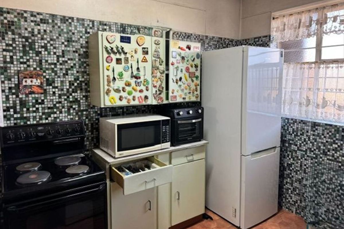 A compact kitchen featuring mosaic tile backsplashes, built-in cabinetry, and an electric stove, offering potential for a modern renovation.