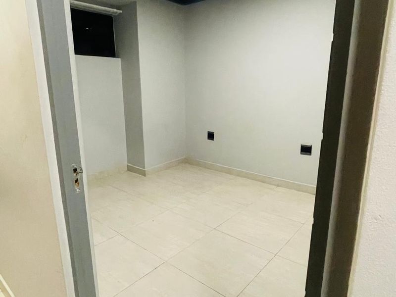An empty, neutral-toned bedroom featuring tiled flooring, recessed lighting, and standard electrical outlets, ready for personalization.