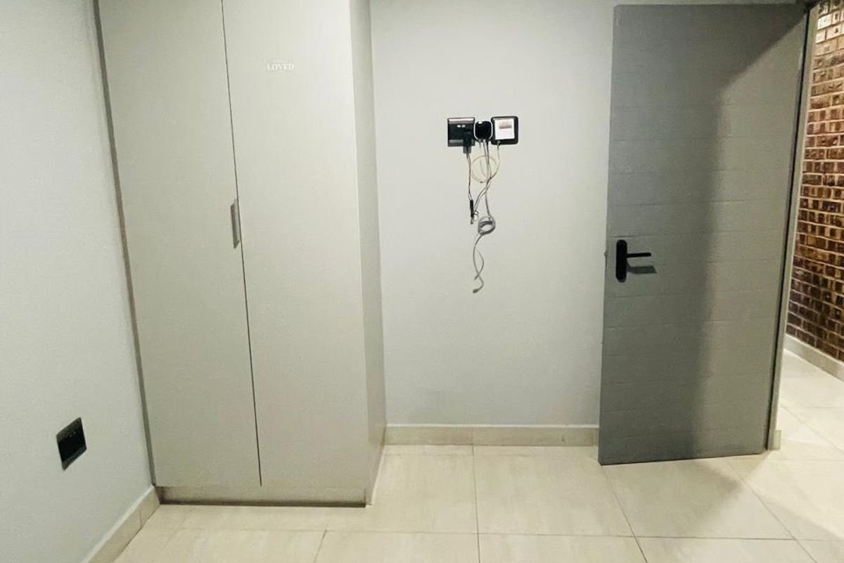 A clean, empty bedroom featuring neutral tiled flooring, a built-in wardrobe, and a modern grey internal door.