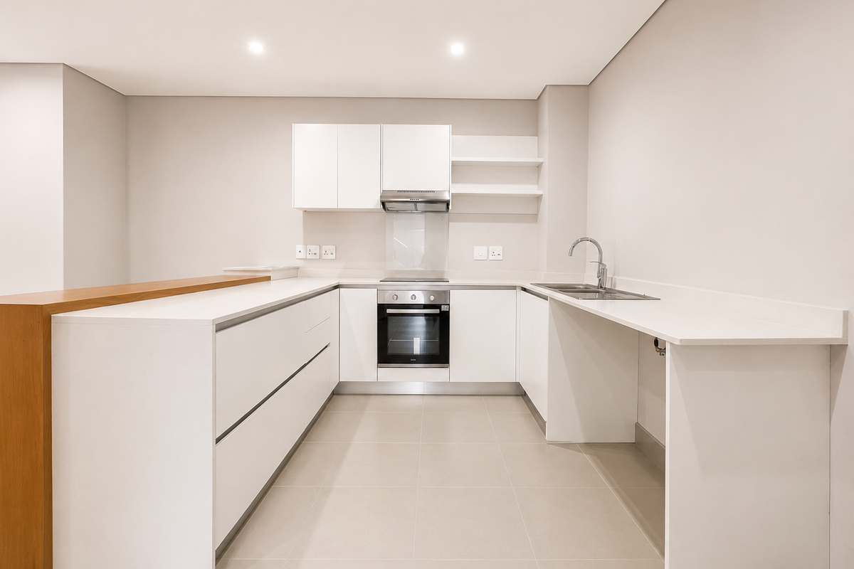 Modern, minimalist kitchen featuring white cabinetry, stone countertops, integrated oven, hob, and extractor fan, with a clean, neutral aesthetic.