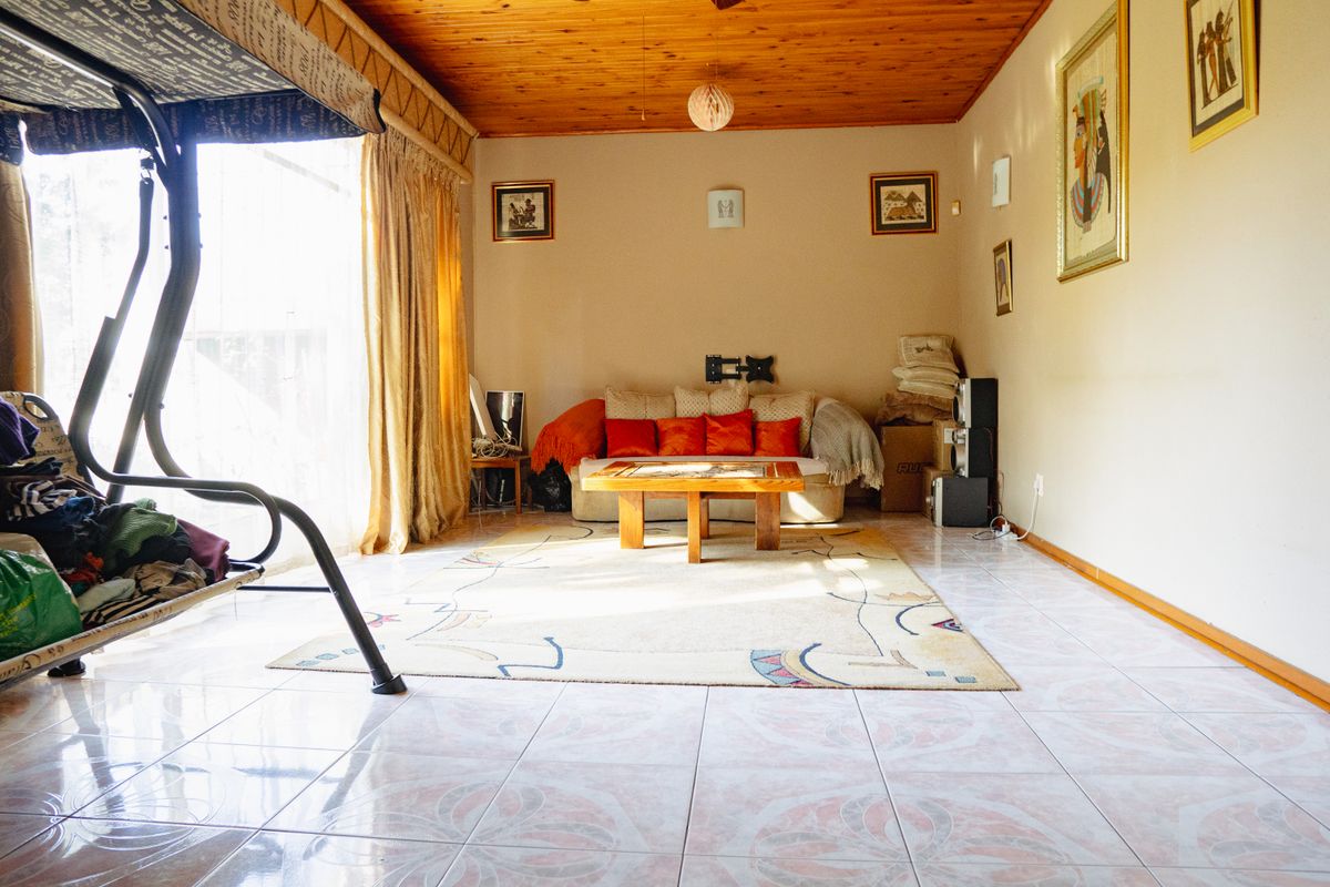 A living room featuring a warm timber-clad ceiling, tiled flooring, and a large sliding glass door providing natural light.