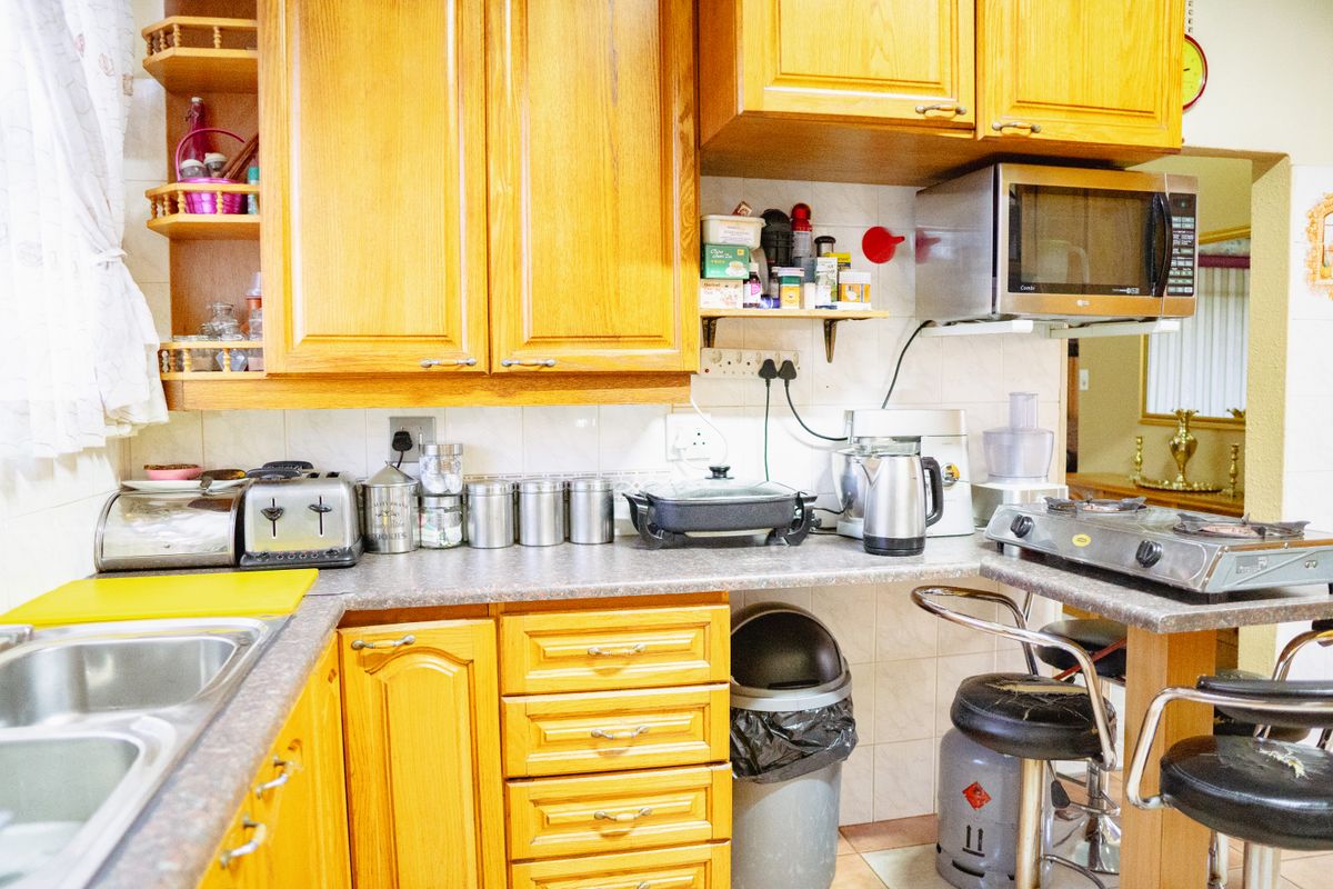 A functional kitchen featuring traditional wood-finish cabinetry, laminate countertops, and a tiled backsplash, offering a classic layout with integrated microwave and sink.
