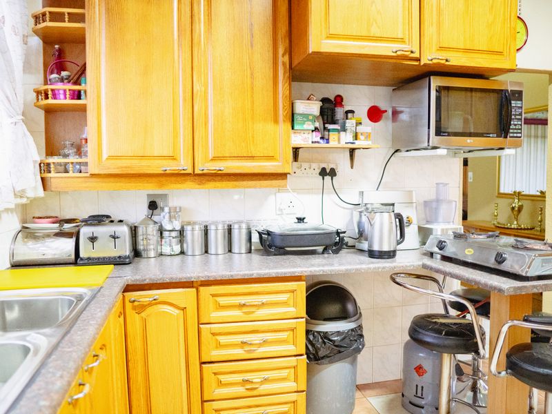 A functional kitchen featuring traditional wood-finish cabinetry, laminate countertops, and a tiled backsplash, offering a classic layout with integrated microwave and sink.